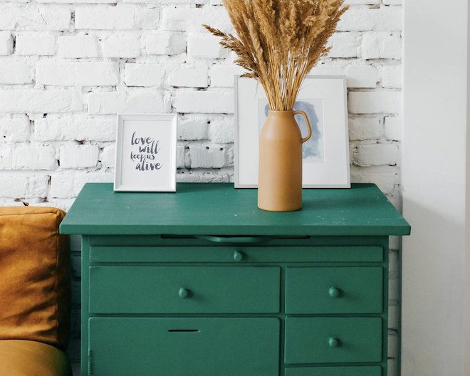 Green drawer with bron flower on top and white brick wall as background